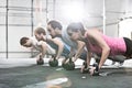 Side view of determined people doing pushups with kettlebells at crossfit gym