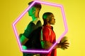 Side view of diverse male players standing back to back by illuminated hexagon on yellow background Royalty Free Stock Photo