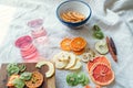 Side view of dried fruits slices in a bowl and on wooden board, fruit candy rolls and two glasses of vitamin water on linen cloth Royalty Free Stock Photo