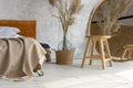 Side view of eco style loft bedroom with  wooden chair, mirror and pampas grass decoration Royalty Free Stock Photo