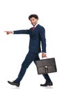 Side view of elegant businessman with bag pointing finger and smiling Royalty Free Stock Photo