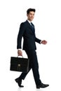 side view of elegant young businessman with suitcase walking and smiling Royalty Free Stock Photo