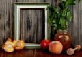 side view of an empty picture frame and fresh ripe peaches with nectarines and a glass jar with peach jam on rustic background Royalty Free Stock Photo