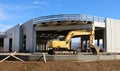 Excavator in front of new commercial building under construction made of prefab concrete blocks. Royalty Free Stock Photo