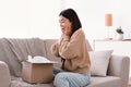 Excited asian lady unpacking parcel after online shopping