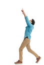 side view of excited casual man pointing fingers in the air and walking Royalty Free Stock Photo