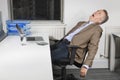 Side view of exhausted middle-aged businessman in front of laptop in office