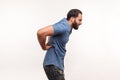 Side view exhausted unhealthy bearded man touching aching back, suffering lower lumbar discomfort, muscle pain, injured spine disk Royalty Free Stock Photo