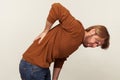 Side view of exhausted unhealthy young man hunching and touching aching back, suffering lower lumbar discomfort Royalty Free Stock Photo