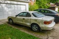 Side view of an extremely dirty white car with a flat front tire in a driveway in front of a white garage door Royalty Free Stock Photo
