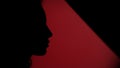 Side view of faded female face placing her finger on lips on dark red background Royalty Free Stock Photo