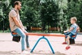 side view of father and son having fun on swing at playground Royalty Free Stock Photo