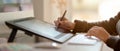 Female graphic designer working on drawing tablet with stylus pen on office desk Royalty Free Stock Photo