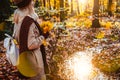 Side view of female holding bouquet of yellow autumn maple leaves in her gloved hands. Ground covered with orange leaves Royalty Free Stock Photo