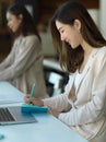 Female office worker working with schedule book in office room with coworker Royalty Free Stock Photo