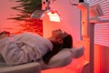 Side view of female patient undergoes red LED light or RLT therapy for skin rejuvenation at modern luxury aesthetic