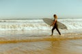 Side view of female surfer in wetsuit with his surfboard entering the sea for riding on waves Royalty Free Stock Photo