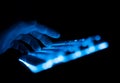 Side view of fingers typing on illuminated RGB keyboard in the dark Royalty Free Stock Photo