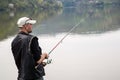 Side View Of Fisherman Reeling String And Throwing Rod In The Calm Lake