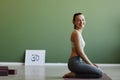 Side view of fit young woman doing yoga indoors and smiling at camera happily Royalty Free Stock Photo