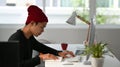 Side view of freelance graphic designer sitting at his workspace and looking at notebook while working on computer. Royalty Free Stock Photo