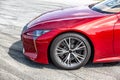 Side view of the front of a red car on asphalt. Bumper, hood, wheel, headlight. Horizontal orientation. Royalty Free Stock Photo