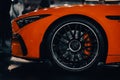 Side view of the front wheel of an orange luxury Mercedes Benz AMG SL with blur background