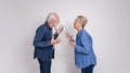 Side view of frustrated senior couple gesturing and arguing with each other against white background