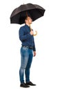 Side view full length of confident businessman standing under his open umbrella looking hopeful ahead isolated on white background Royalty Free Stock Photo