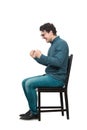 Side view full length hysterical and passionate businessman sitting on chair, keeps fists tight, shouting and screaming, isolated Royalty Free Stock Photo