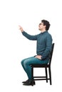 Side view full length portrait of cheerful businessman seated on a chair hand outstretched as pressing an invisible object or Royalty Free Stock Photo