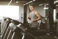 Side view full length of young man in sportswear running on treadmill at gym. Flare effect, copy space Royalty Free Stock Photo