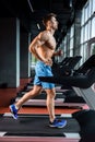 Side view full length of young man in sportswear running on treadmill at gym Royalty Free Stock Photo