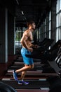 Side view full length of young man in sportswear running on treadmill at gym Royalty Free Stock Photo