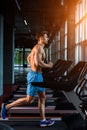 Side view full length of young man in sportswear running on treadmill at gym Royalty Free Stock Photo