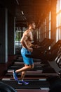 Side view full length of young man in sportswear running on treadmill at gym Royalty Free Stock Photo