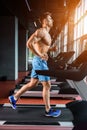 Side view full length of young man in sportswear running on treadmill at gym Royalty Free Stock Photo