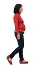 Side view of full portrait of a pregnant woman with casual clothes walking on white background Royalty Free Stock Photo