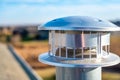 side view of a Galvanized metal chimney exhaust on asphalt roof with a rain cap