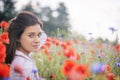 Side view of girl with hand in her hair posing in red poppies field Royalty Free Stock Photo
