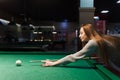 side view at the girl plays billiards in a dark pub Royalty Free Stock Photo