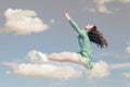 Young woman in dress flying in the sky.