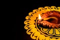 Side view of glowing earthen oil lamp and rangoli on black background with a copy space. diwali concept