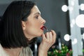 Side view of a gorgeous young woman applying red lipstick. Brunette female with red lips making makeup and looking to the mirror Royalty Free Stock Photo