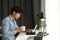 Side view of a graphic designer is working with computer tablet and drinking coffee at his workspace. Royalty Free Stock Photo