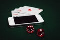 Side view of a green poker table with a smartphone, cards and dices. Gambling online app addiction. Royalty Free Stock Photo