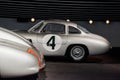 Side view of grey retro car with black number 4 in white circle painted on left door, wooden steering wheel, windshield Royalty Free Stock Photo