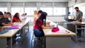 Side view of group of multiracial students studying and using laptops in class with male teacher. Royalty Free Stock Photo