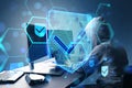 Side view of hacker at desktop using laptop with glowing hexagonal shield hologram with binary coding on blurry background. Safety Royalty Free Stock Photo