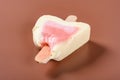 Half eaten strawberry flavor popsicle on a brown background no logo no trademark Royalty Free Stock Photo